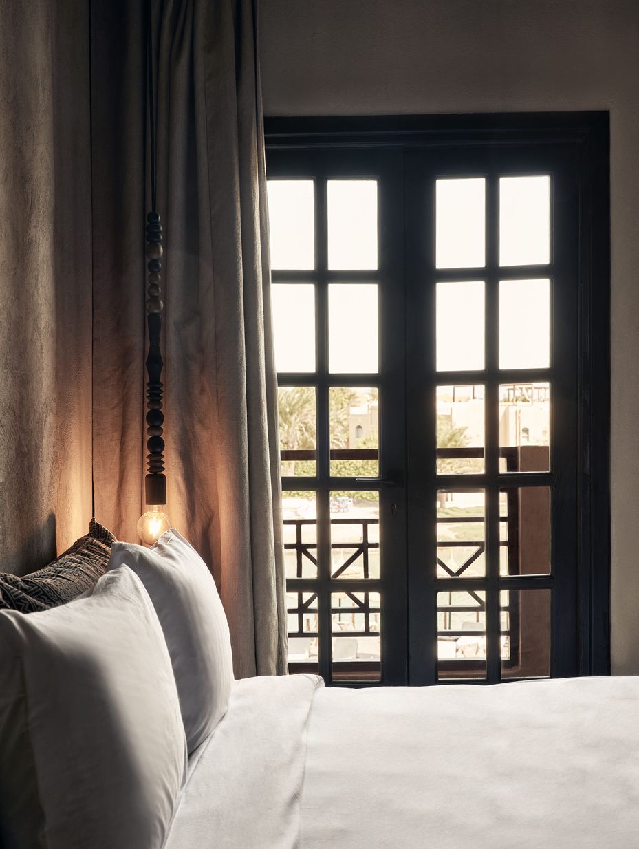 Bed and pendant light beside a tall window at Cook’s Club Hotel